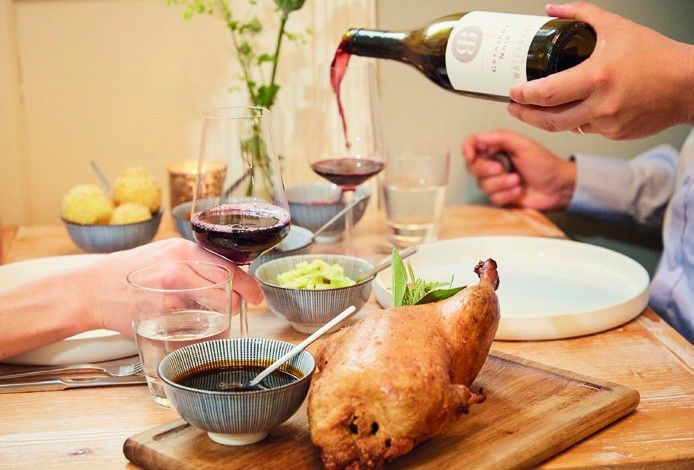 Ente To Go zu Hause am Tisch, Rotwein wird eingeschenkt